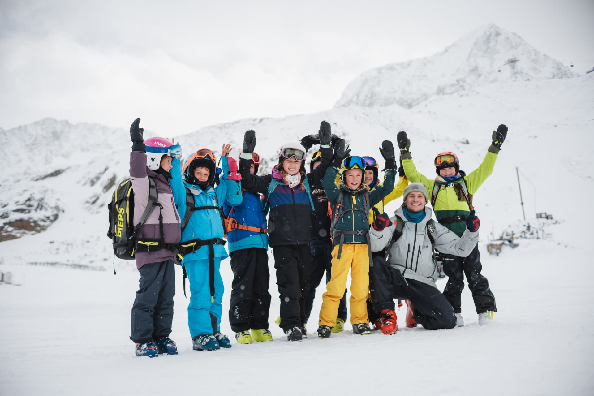 Kinder und Jugendliche der Freeride Academy Innsbruck jubeln mit Coach beim Saisonauftakt im verschneiten Hochgebirge
