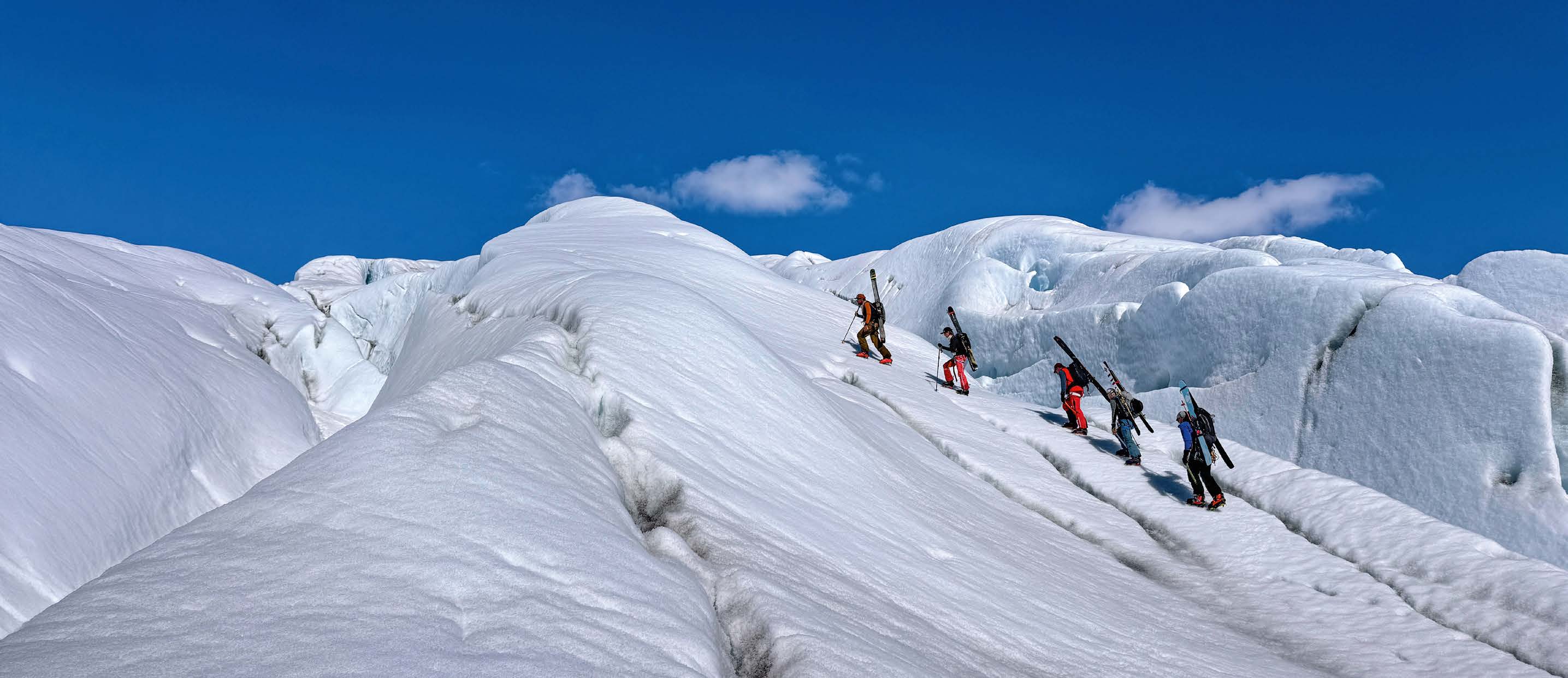Skitourengruppe steigt zwischen Gletscherspalten und Eisformationen auf