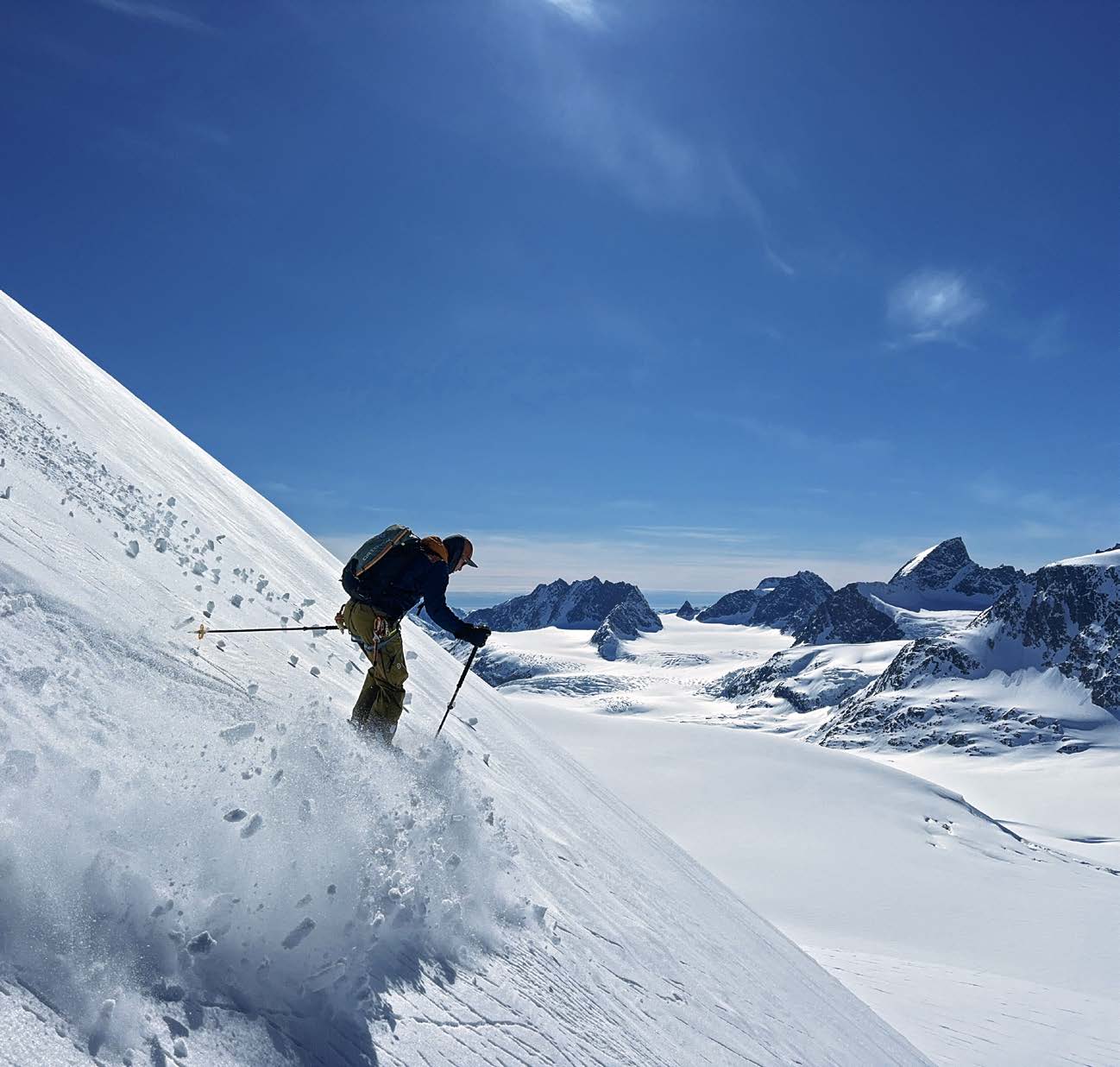 Skifahrer fährt einen Gletscherhang mit Blick über Grönlands Eisfelder ab