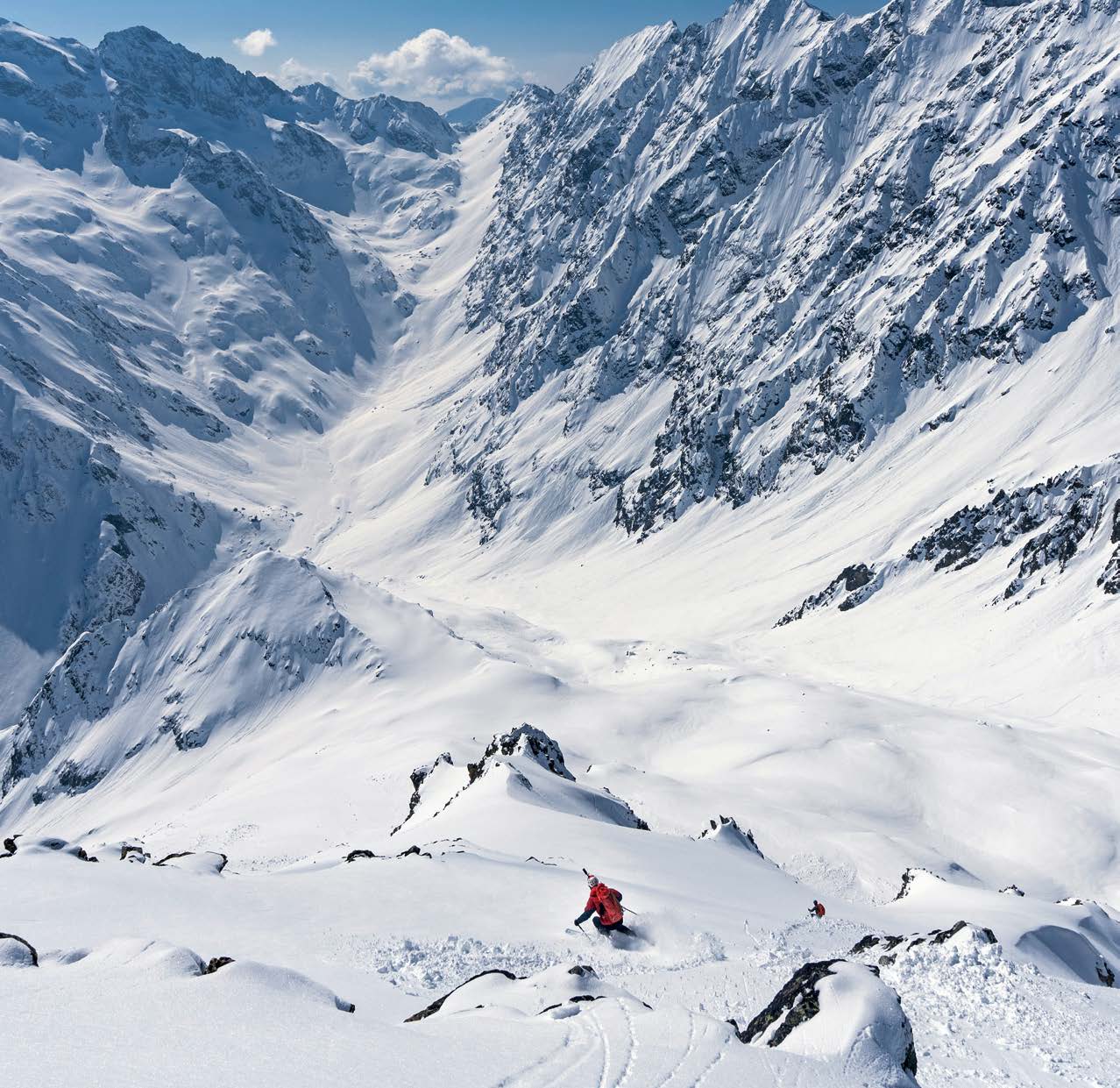 Weites verschneites Hochtal in den Westalpen mit zwei kleinen Skitourengehern