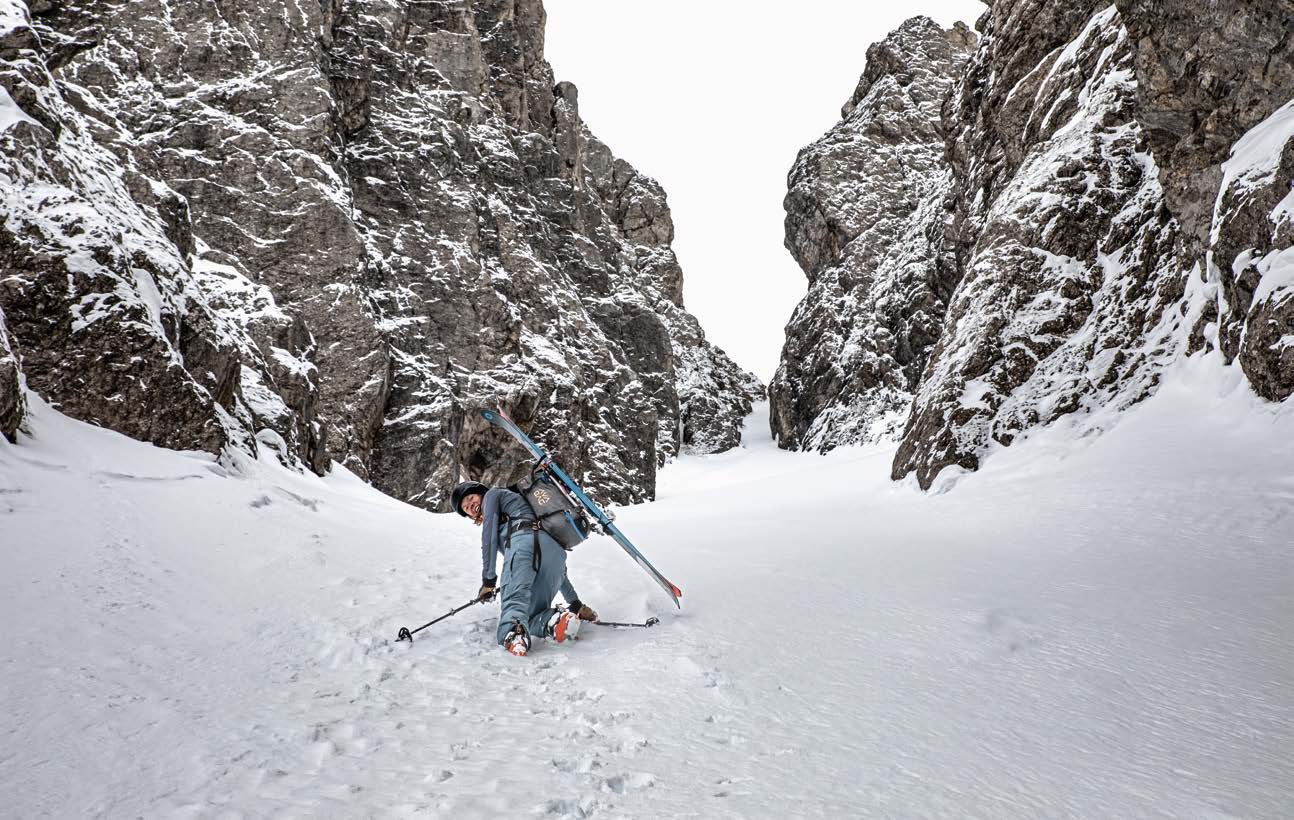 Skitourengeherin im Aufstieg durch ein enges Couloir zwischen Kalkfelsen