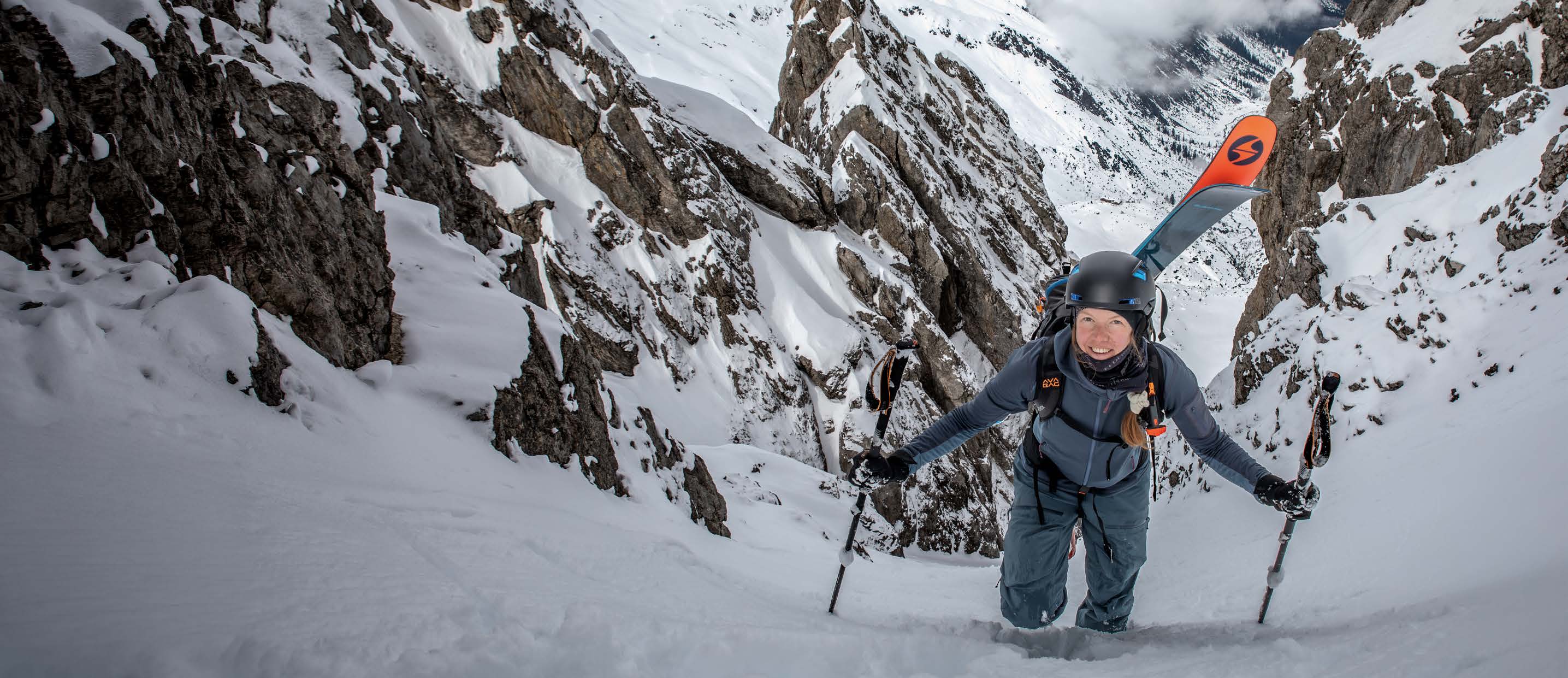 Skibergsteigerin stapft mit Ski am Rucksack durch das Butterfly Couloir im Lechtal