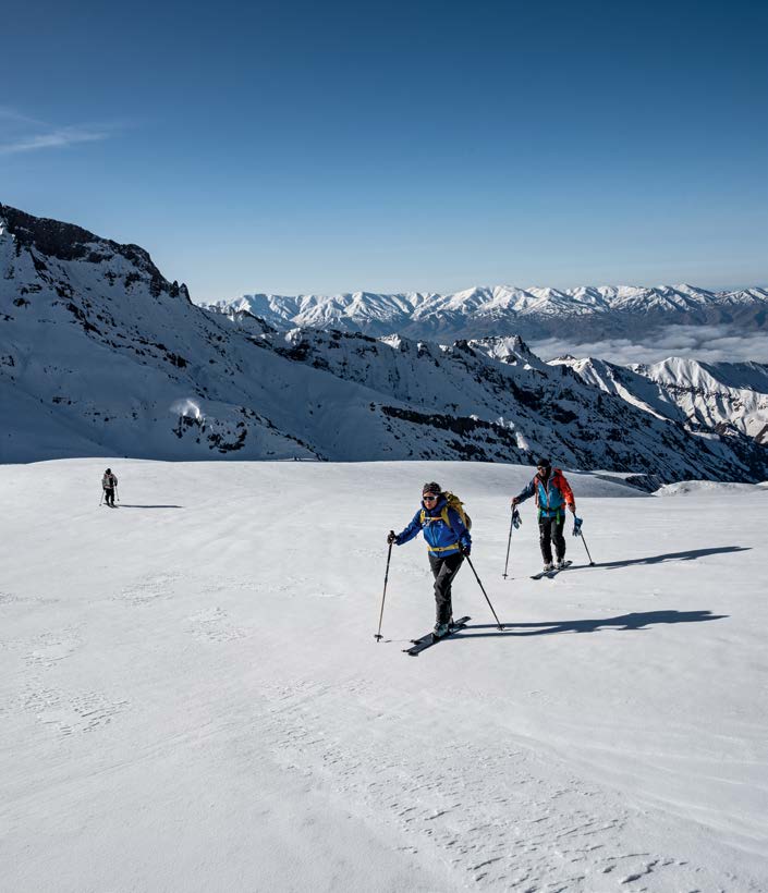 Drei Skitourengeher steigen vor schneebedeckten Alborz-Gipfeln auf