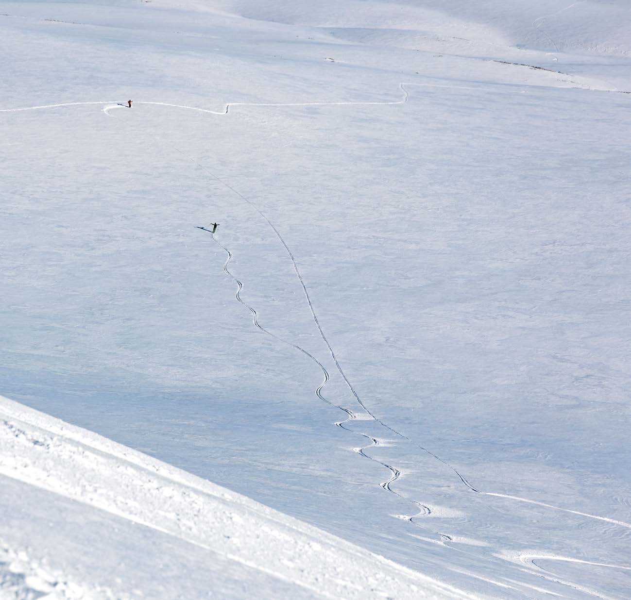 Winzige Skispuren auf einem weiten, sonnigen Schneehang in Norwegen