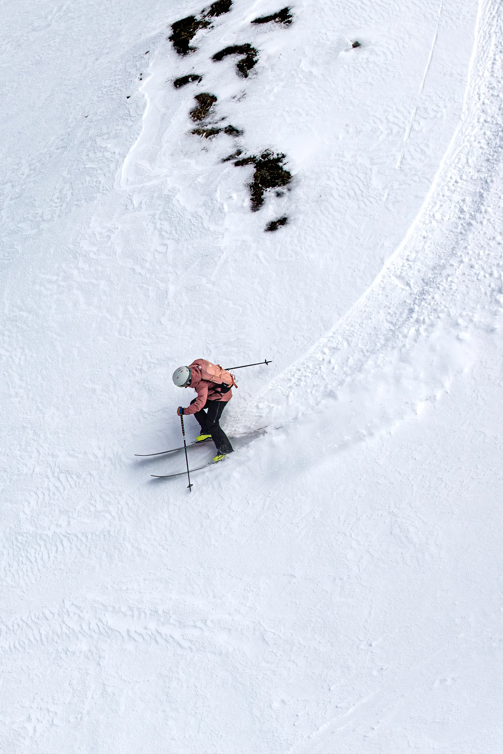 Andrea Limbacher fährt durch einen weitläufigen Tiefschneehang mit sichtbaren Skispuren in Lenzerheide, aus erhöhter Perspektive.