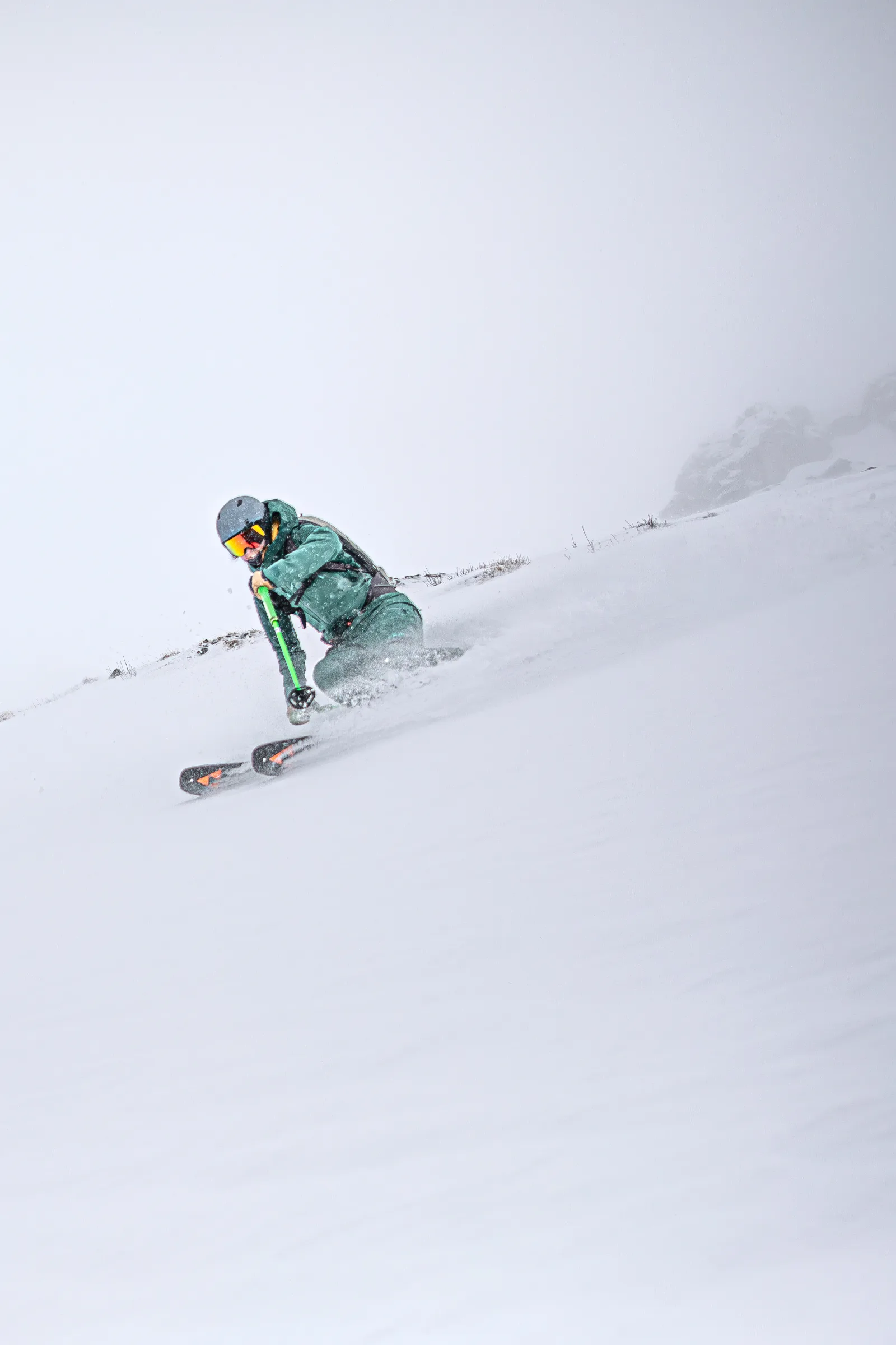 Annika Schlachter fährt in grüner Skikleidung tief in die Hocke gebeugt durch den Schnee an einem nebligen Hang in Gastein, während hinter ihr Felsen hervorragen.