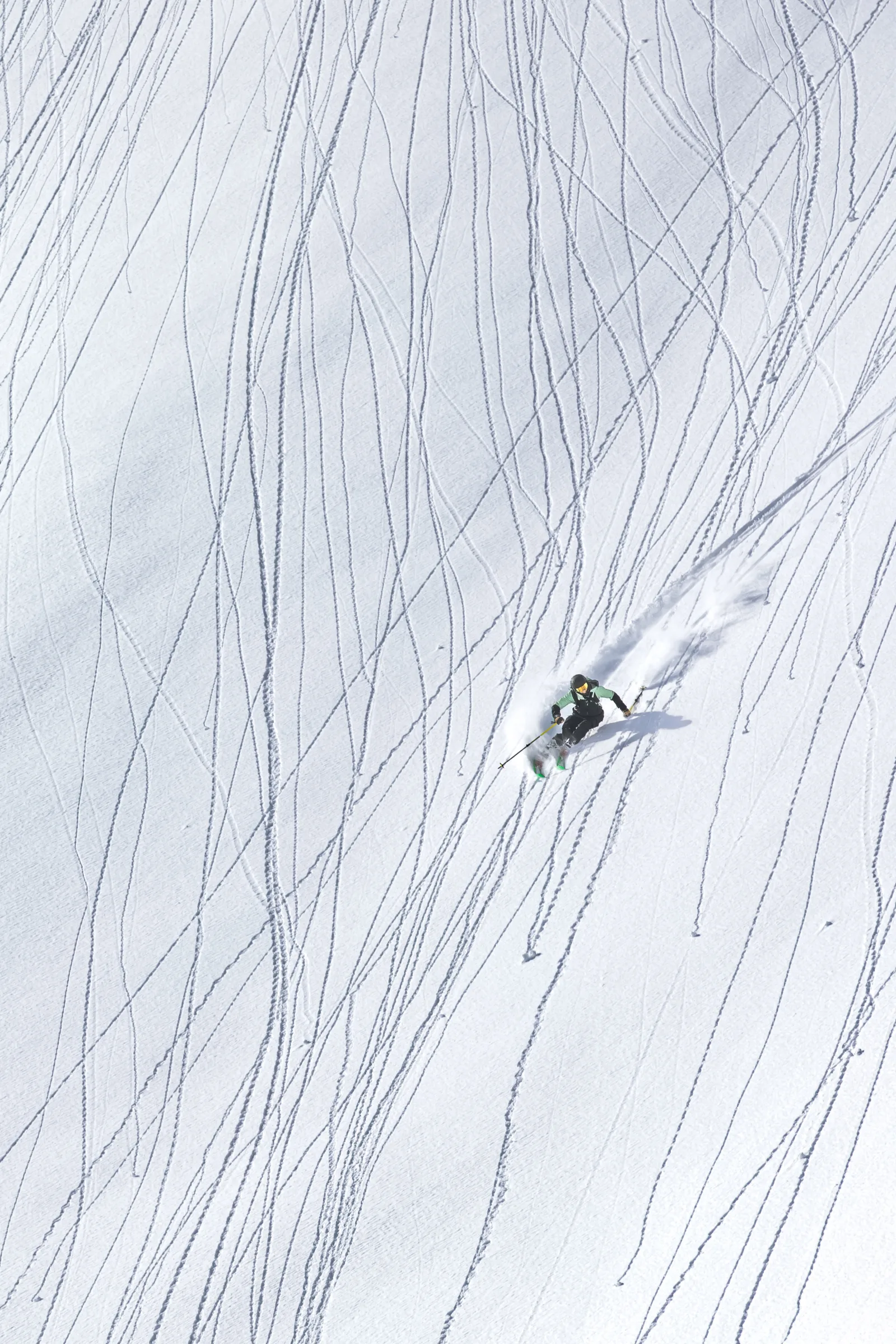 Von oben gesehen fährt Annika Schlachter mit grünen Ski über einen von schmalen Spuren durchzogenen Hang, eine Schneefahne hinter sich.