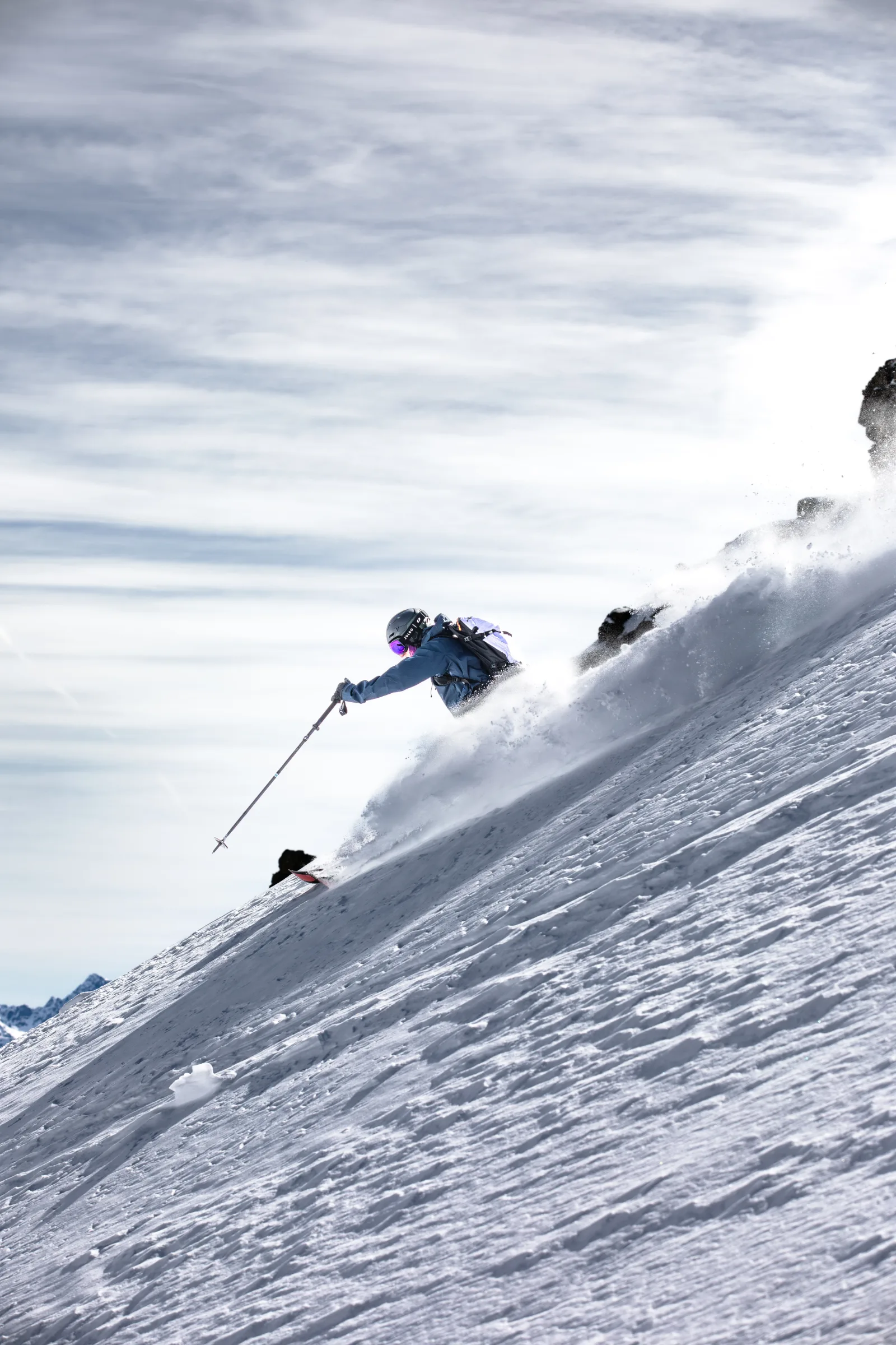 Christoph Öfele beugt sich auf einem steilen Hang tief in einen Schwung und streckt einen Skistock nach vorn, während Schnee neben ihm aufwirbelt.