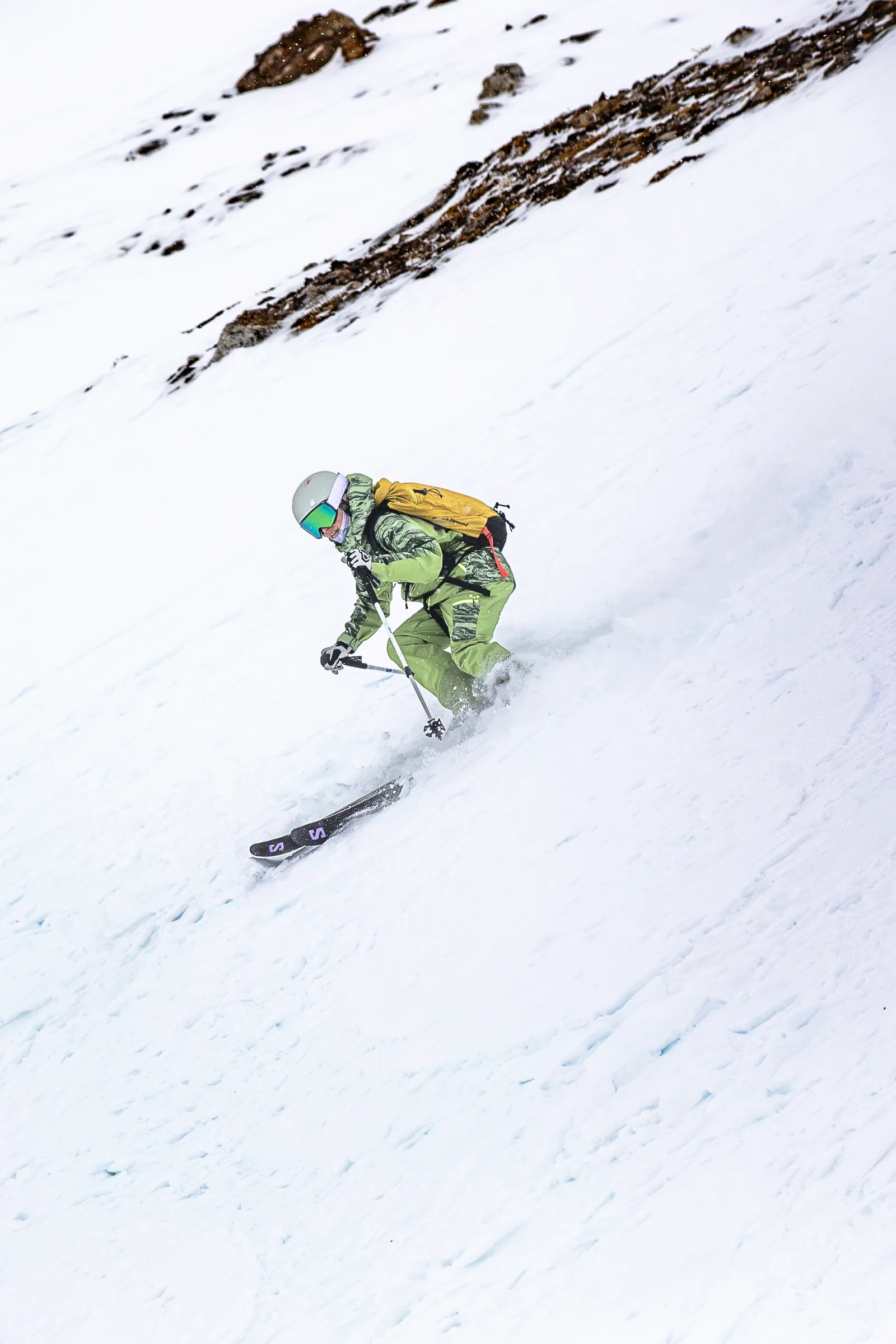 Martina Wengenmeir fährt mit tief gebeugten Knien durch den Schnee unterhalb eines Felsbands, die Skistöcke vor dem Körper.