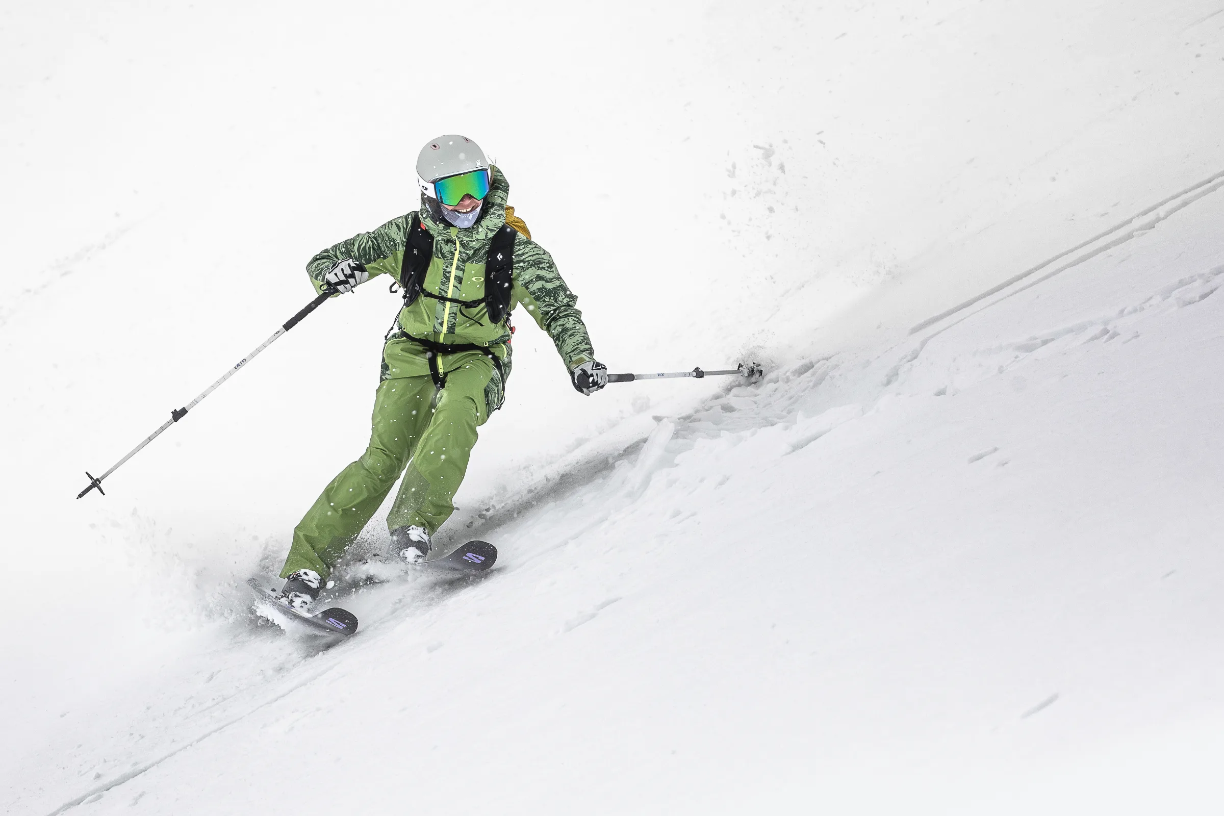 Martina Wengenmeir fährt in grüner Skikleidung auf die Kamera zu und zieht mit ihren Ski zwei Spuren durch den offenen Schneehang.