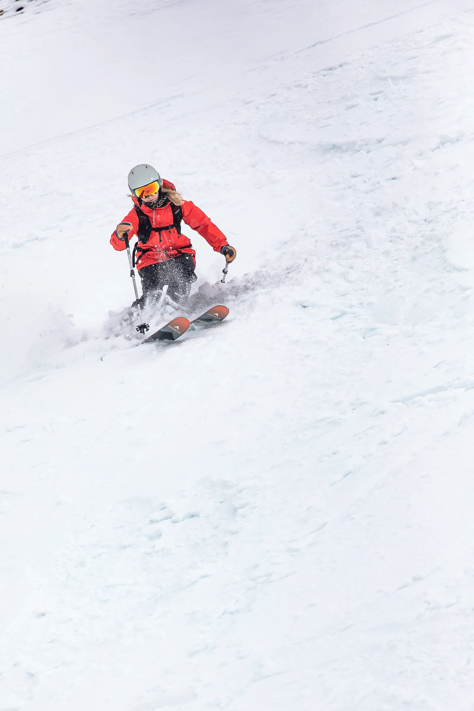 Pia Vogt fährt frontal auf die Kamera zu und wirbelt auf einem offenen Schneehang Schnee um ihre Skispitzen auf.